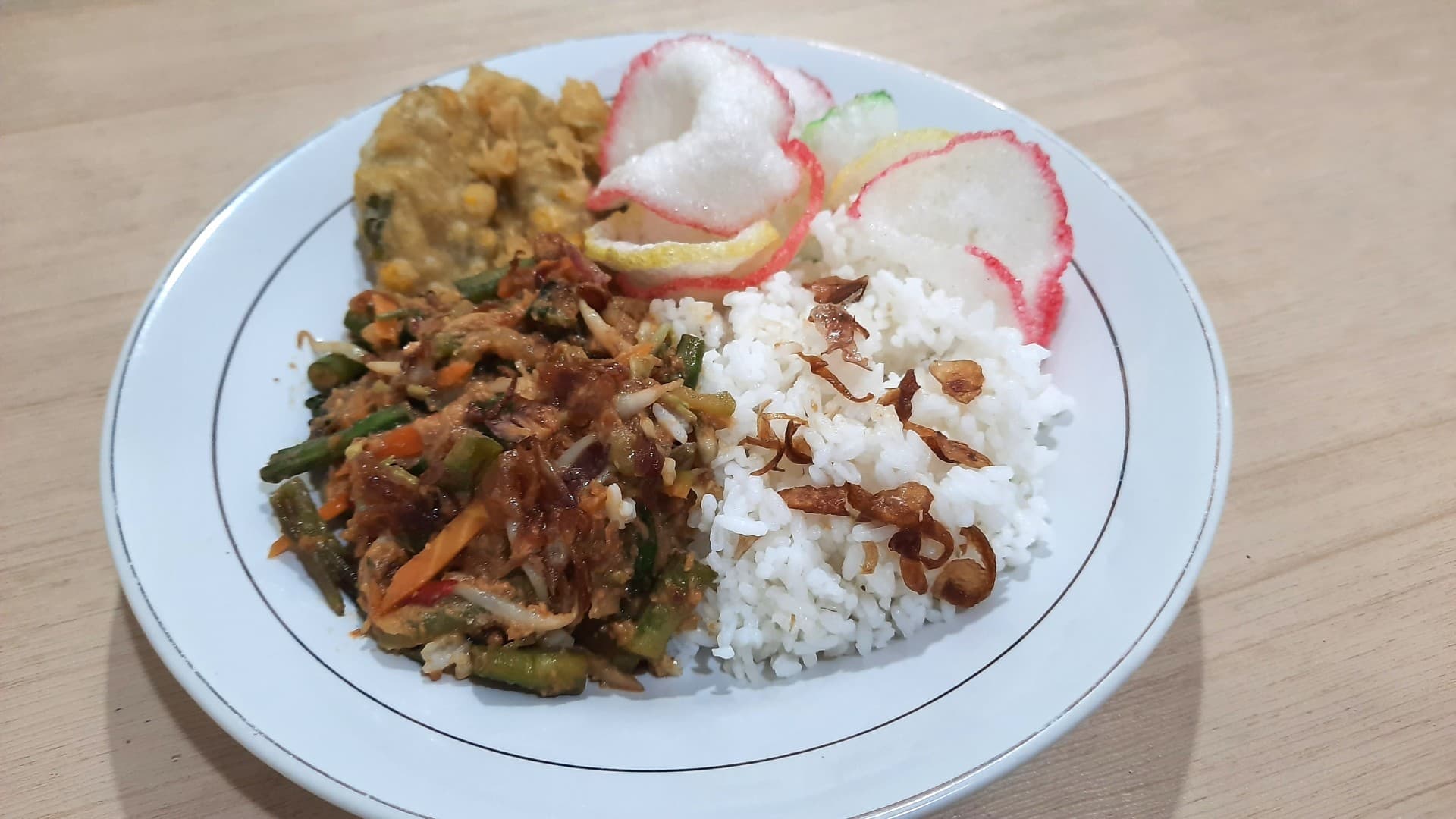 Sepiring nasi pecel dengan sayuran rebus, sambal kacang, dan kerupuk